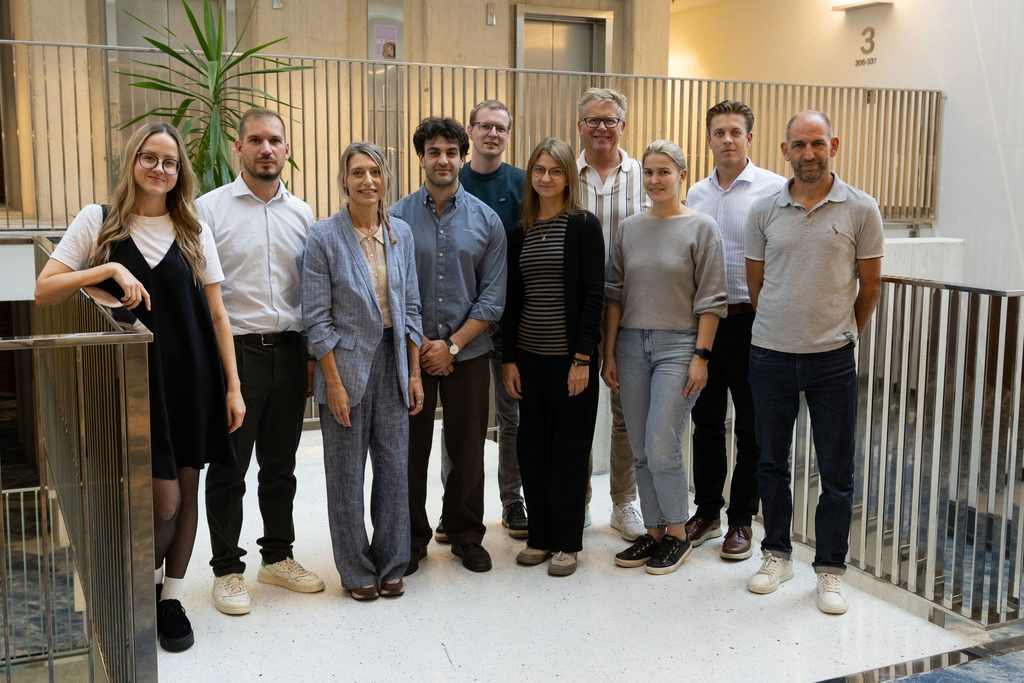 Ten people stand in a conference building staircase and stand posting for a camera.